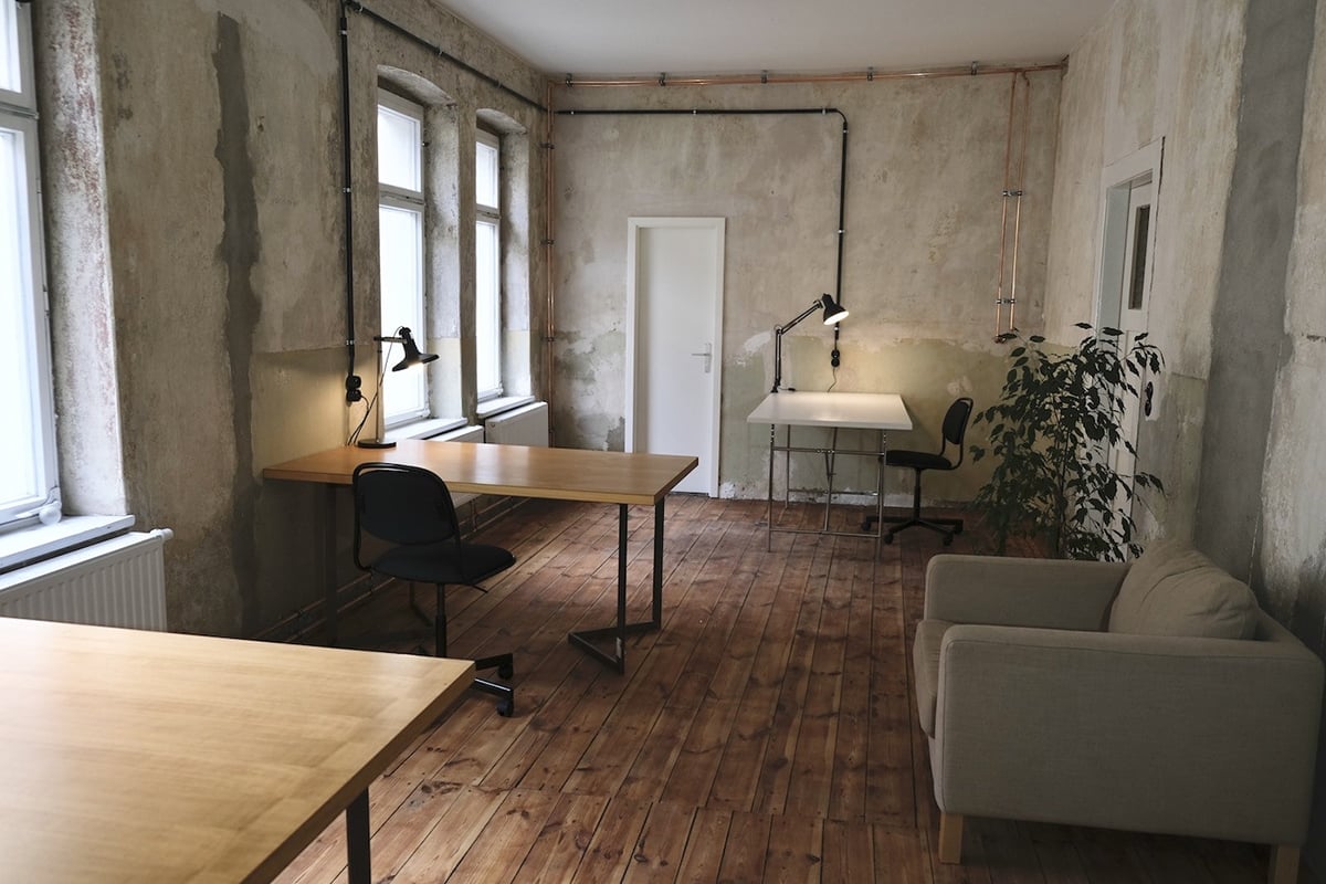 Raum mit Holzfussboden, Schreibtischen und Sofa